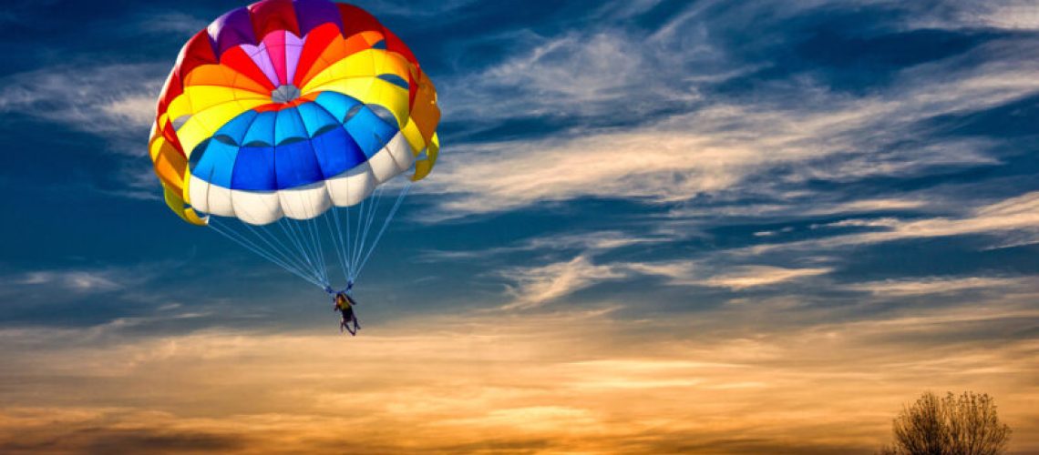 A man is gliding with a parachute on the background of sunset.